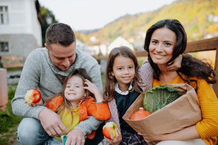 Sisters and parents in park during warm autumn day.の写真素材