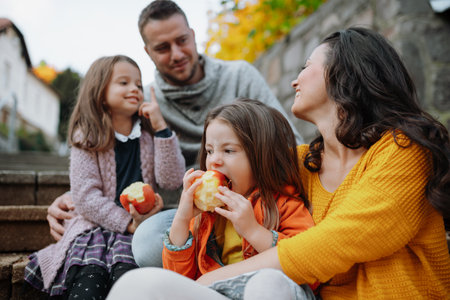 Sisters and parents in park during warm autumn day.の写真素材