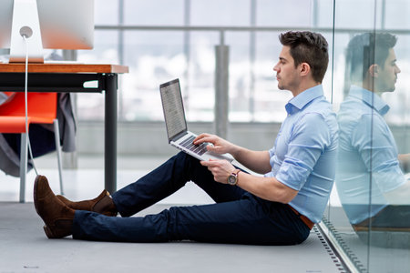 Young engineer working in office, sitting on floor.