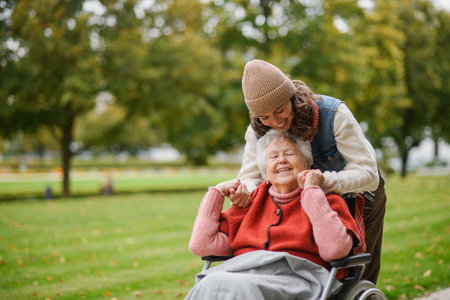 Granddaughter on an autumn walk in the park with her grandmother in wheelchair.の写真素材