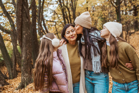 Mature daughter, grandmother and granddaugters on walk in autumn forest.の写真素材
