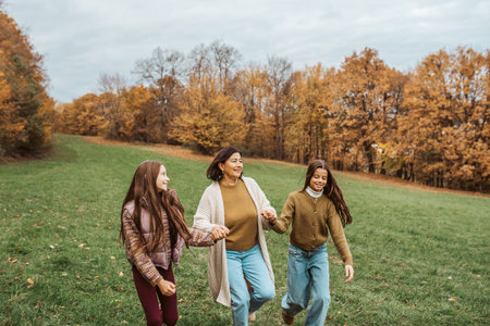 Grandmother spending time with granddaugters, walking in autumn nature.の写真素材