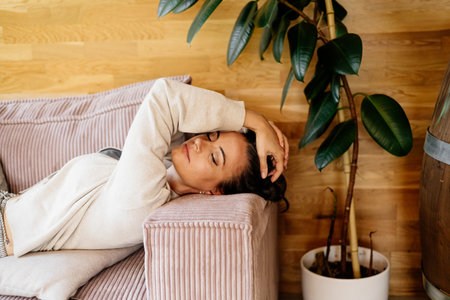 Relaxed woman taking a break, resting on sofa with closed eyes.の写真素材