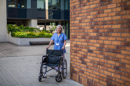 Nurse in uniform pushing empty wheelchair.の写真素材
