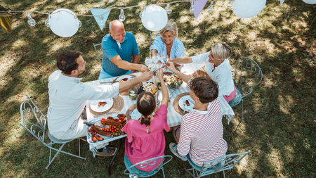 Areal view of multigenerational family toasting during outdoor barbecue party.の写真素材