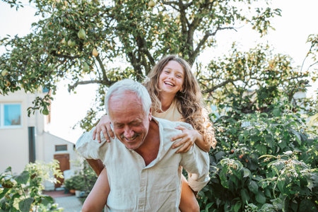 Grandfather playing with granddaughter in the garden.の写真素材