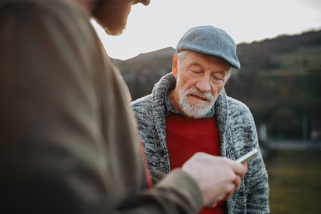 Man showing older person something in smartphone.の写真素材