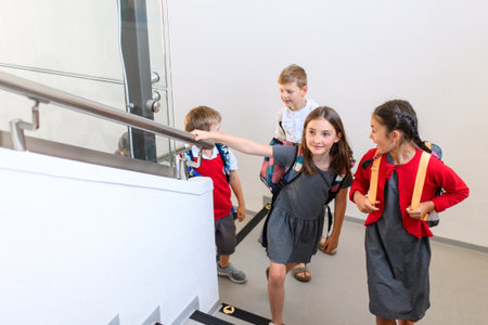Children with backpacks climbing stairs at school.の写真素材