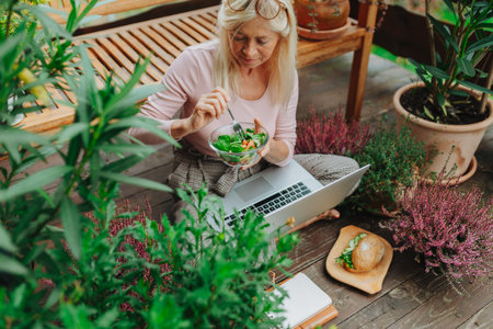 Older woman having lunch while working from homeoffice.の写真素材