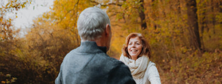 Hugging older couple spending time outdoors in fall season.