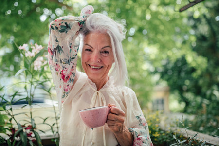 Portrait of beautiful senior woman standing on balcony with morning cup of coffee.の写真素材