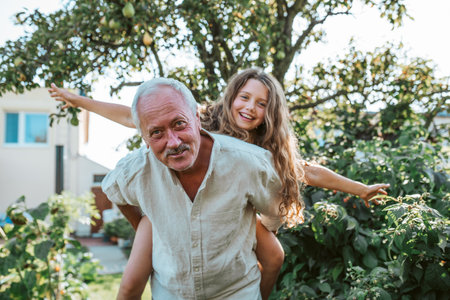 Grandfather playing with granddaughter in the garden.の写真素材