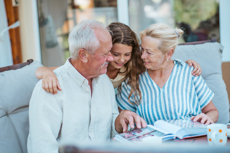 Senior couple showing family photo album to granddaughter.