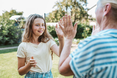 Grandmother and granddaughter playing clapping game.