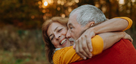 Romantic moment between senior couple, standing in autumn nature.