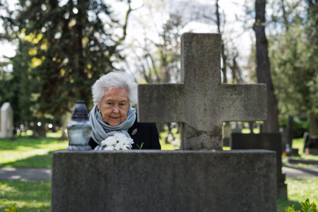 Old lady remembering a loved one at a grave.