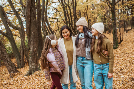 Mature daughter, grandmother and granddaugters on walk in autumn forest.の写真素材