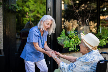 Tender moment between older caregiver and senior female patient in wheelchair.