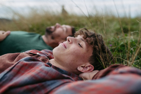 Top view of father and teen boy lying in grass and resting during hiking trip.