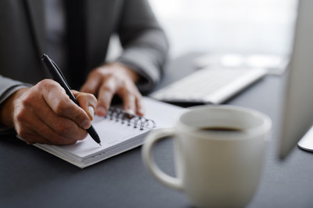 Close up of mans hands taking notes at workplace.