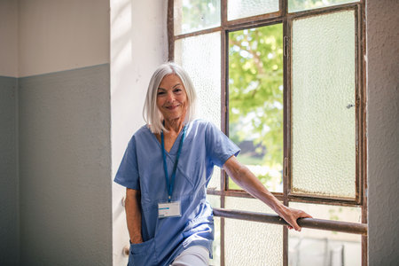 Tired nurse taking break, standing by old window.の写真素材