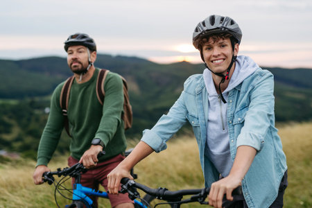 Dad and teen boy riding bicycles in mountains. Cycling trip during autumn day.