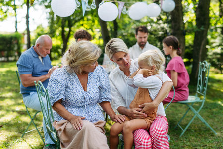 Smiling grandmother talking with her daughter, holding grandchild, family gathering.