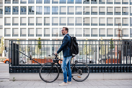 City commuter walking with bike to office, wearing backpack and helmet.の写真素材