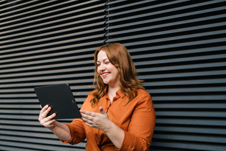 Woman holding tablet, black background.の写真素材