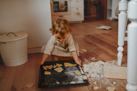 Toddler learning to bake holiday cookies at home.の写真素材