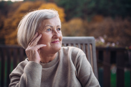 Portrait of smiling elderly lady relaxing on terrace during warm autumn day.の写真素材