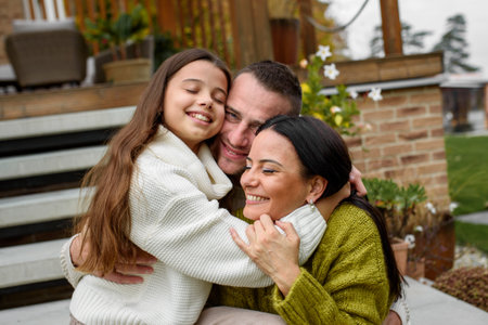 Family portrait of parents with young daughter, sitting on home patio stairs.の写真素材