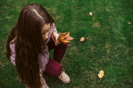 Girl picking fallen autumn leaves in hand, close up.