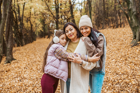 Mature daughter, grandmother and granddaugter on walk in autumn forest.の写真素材