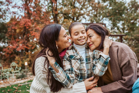 Mother, grandmother and granddaugter standing in autumn garden.の写真素材