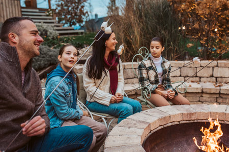Family roasting marshmallows over open flame, campfire on backyard.の写真素材