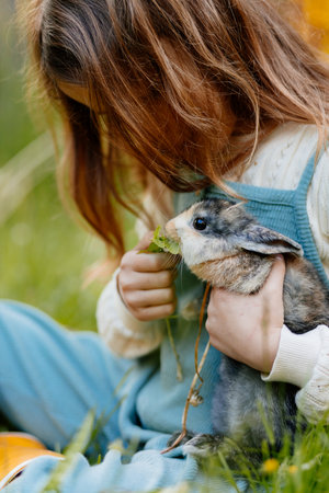 Young girl feeding pet bunny with vegetable leaves.の写真素材