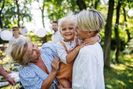 Smiling grandmother talking with her daughter, holding grandchild, family gathering.の写真素材