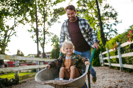 Father pushing toddler boy in wheelbarrow.の写真素材