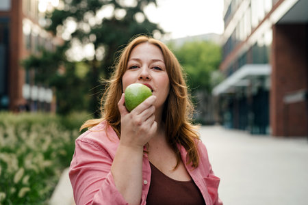 Plus size woman holding green apple.