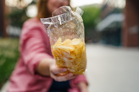 Curvy woman offering from bag of chips.の写真素材