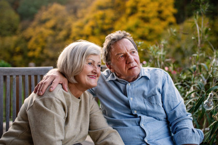 Peaceful moment for senior couple, enjoying warm autumn evening on terrace.の写真素材