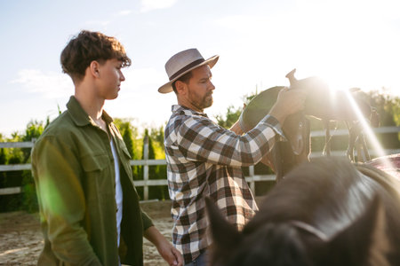 ather and son preparing horse for riding.の写真素材