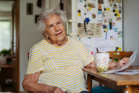 Senior woman enjoying morning coffee and daily news in kitchen.