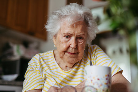 Portrait of worried senior woman in kitchen.