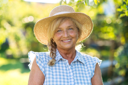 Happy elderly woman enjoying sunny day in garden.