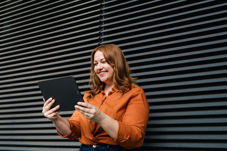 Woman holding tablet, black background.の写真素材