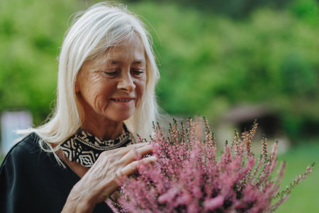 Mature woman standing by potted heathers.