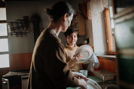 Girl helping mother to wash dishes in an old rural kitchen.の写真素材