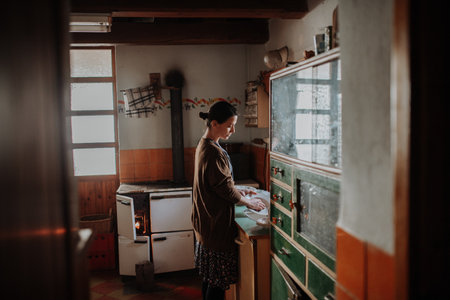 Woman washing dishes in an old rural kitchen.の写真素材
